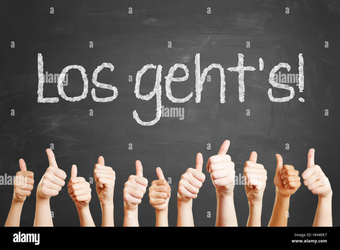 Slogan allemand 'Los geht's" (let's go) écrit à la craie sur tableau noir avec Thumbs up pour la motivation Banque D'Images