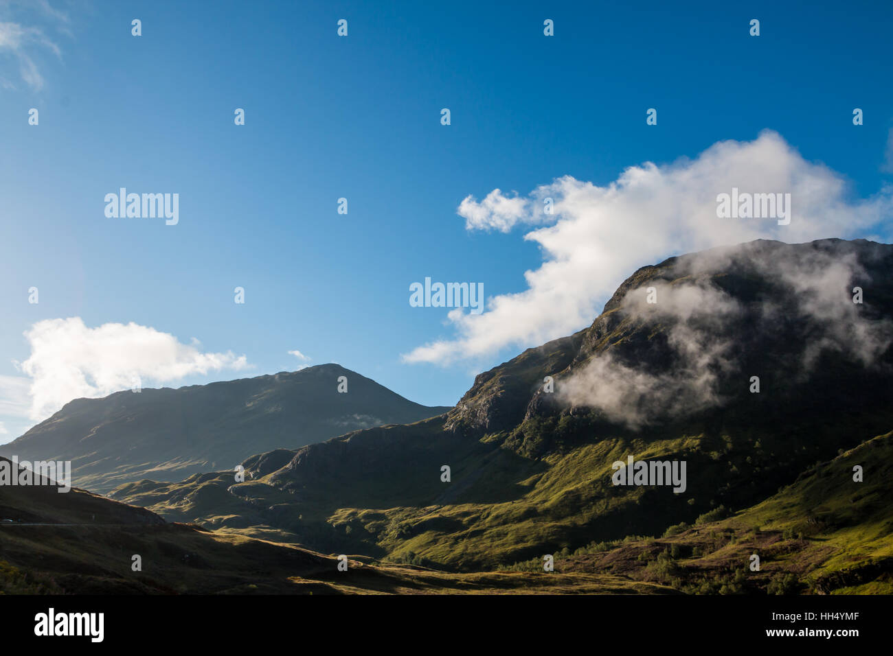 La brume s'élève de montagne à Glencoe sur fond bleu, journée ensoleillée, l'Écosse, Août Banque D'Images