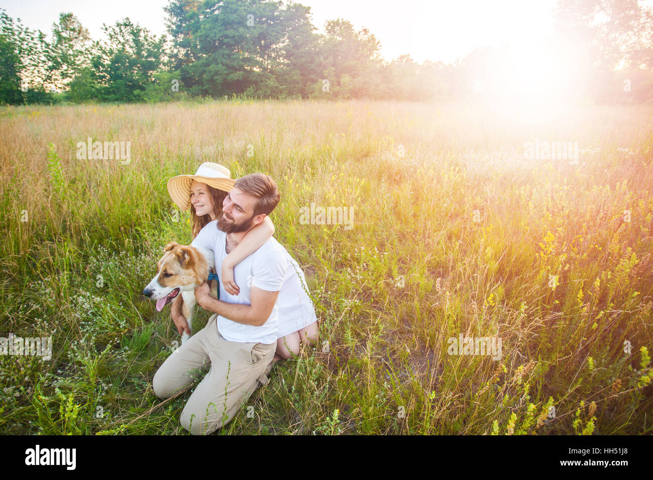 Beau couple heureux avec leur chien Alabai dans la nature avec le coucher du soleil. Banque D'Images