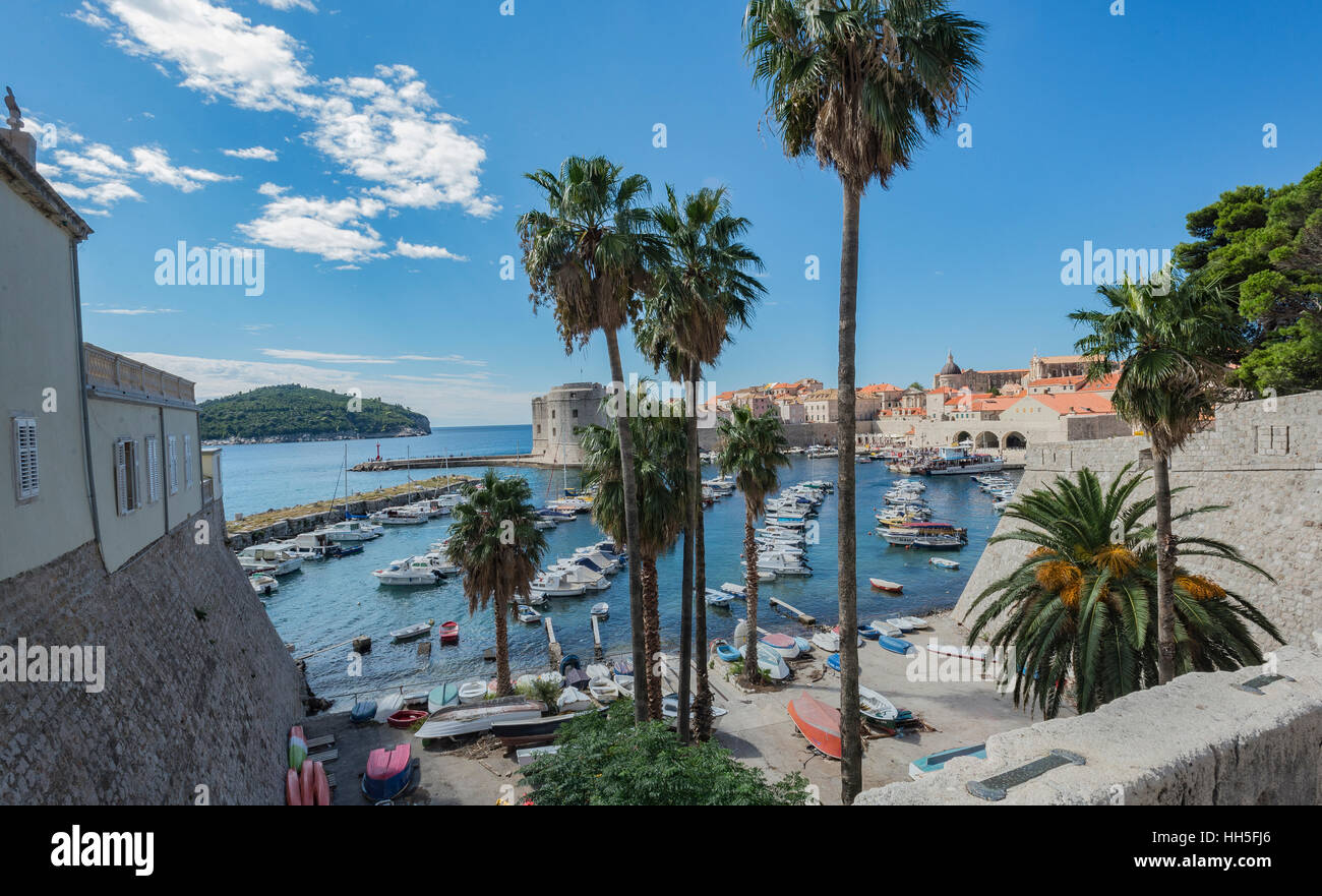 L'extérieur de l'ancien mur de la ville à la recherche à la Dubrovnik, Croatie port avec ses bateaux et de palmiers. Banque D'Images