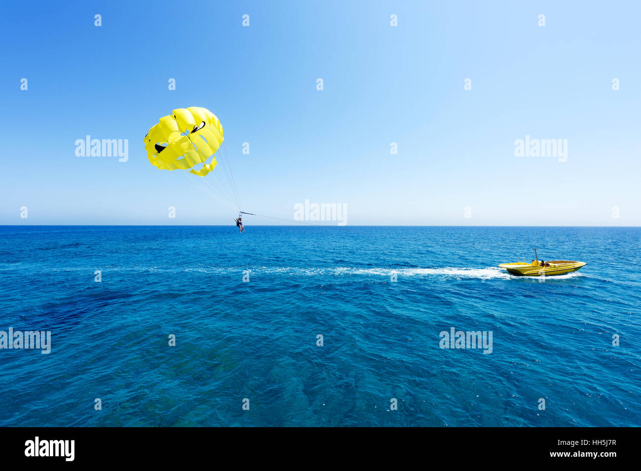 Photo de mer à Protaras, Chypre île avec le parapente jaune avec des gens en forme de crâne avec des yeux noirs et un bateau, l'eau et bleu immaculé Banque D'Images