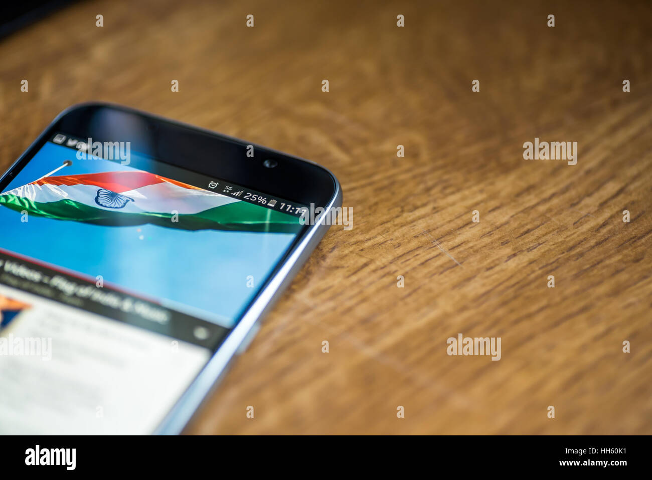 Sur fond de bois avec smartphone 5G Réseau inscription 25  % et l'Inde drapeau sur l'écran. Banque D'Images