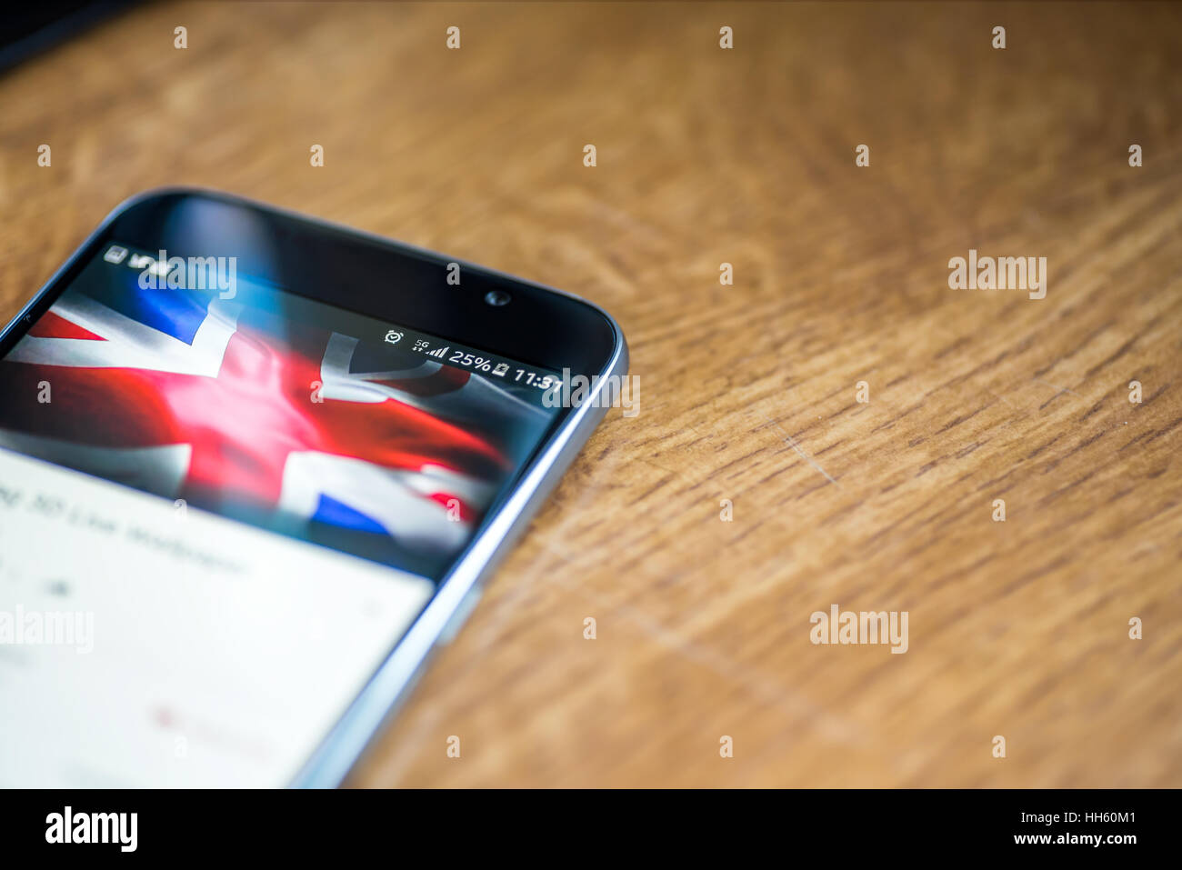 Sur fond de bois avec smartphone 5G Réseau inscription 25  % et UK drapeau sur l'écran. Banque D'Images