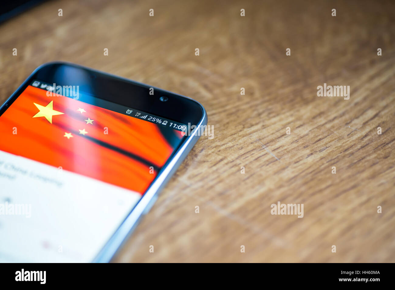 Sur fond de bois avec smartphone 5G Réseau inscription 25  % et la Chine drapeau sur l'écran. Banque D'Images