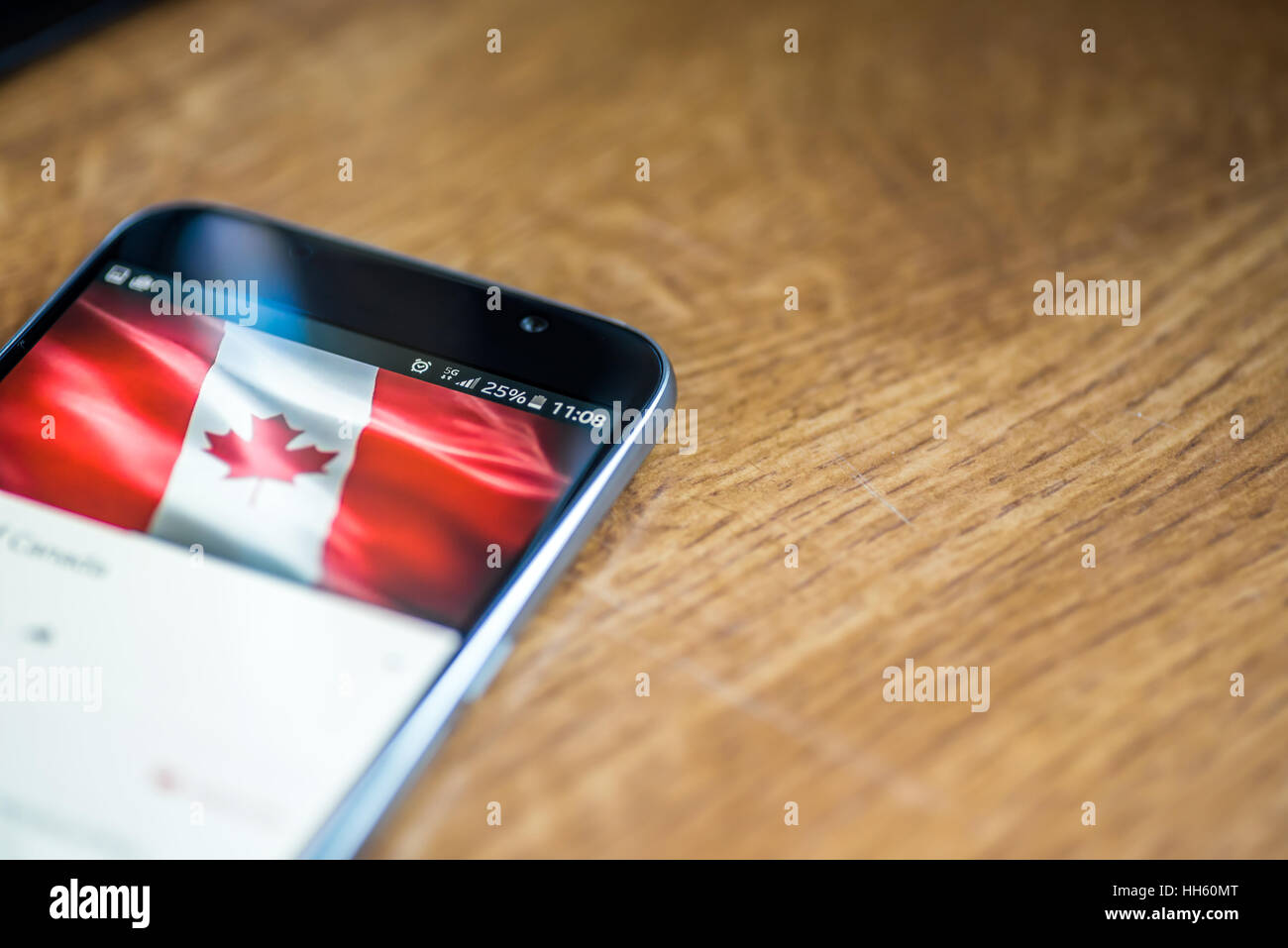 Sur fond de bois avec smartphone 5G Réseau inscription 25  % et le Canada drapeau sur l'écran. Banque D'Images
