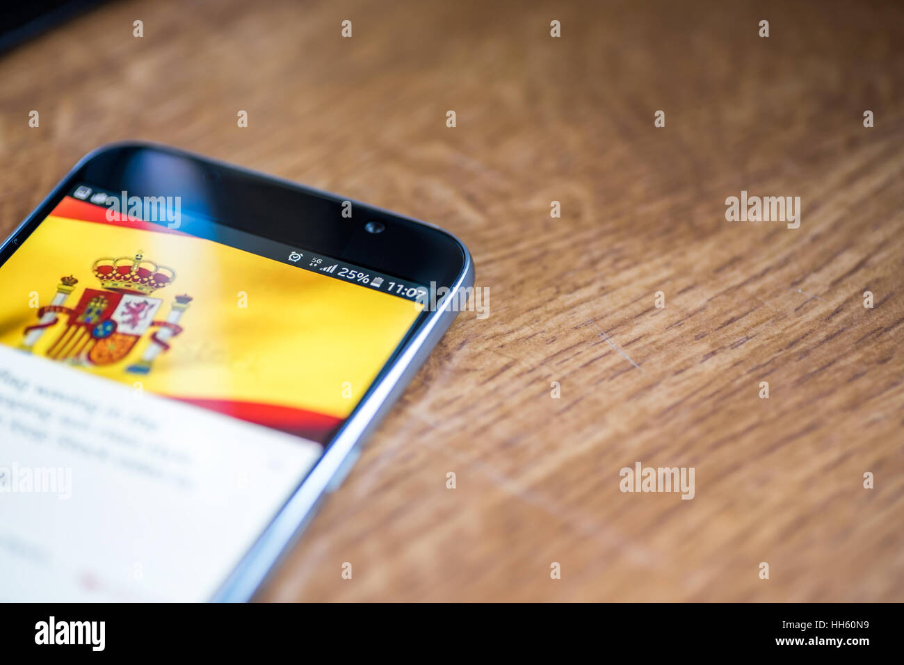 Sur fond de bois avec smartphone 5G Réseau inscription 25  % et l'Espagne drapeau sur l'écran. Banque D'Images