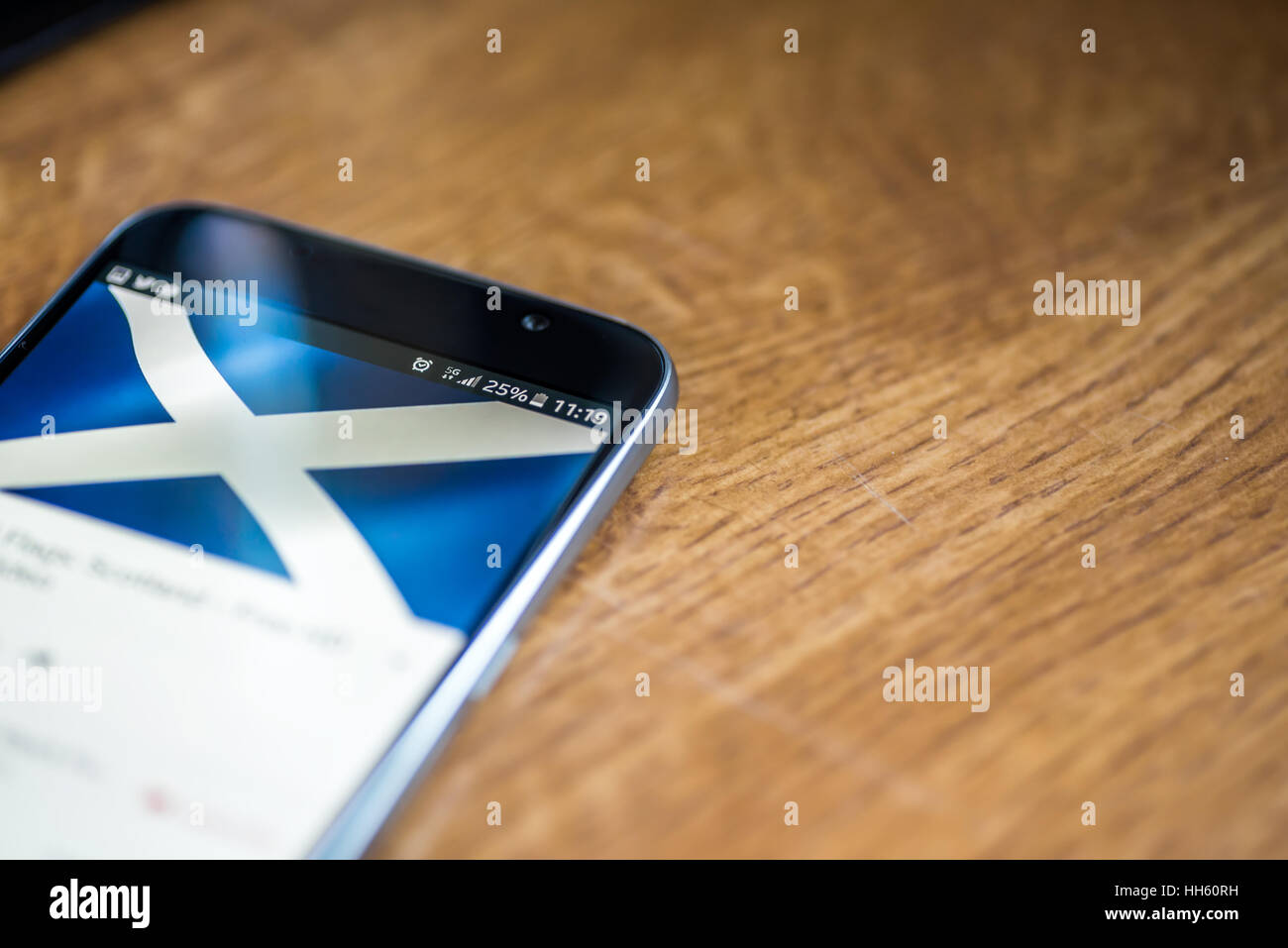 Sur fond de bois avec smartphone 5G Réseau inscription 25  % et de l'Écosse drapeau sur l'écran. Banque D'Images