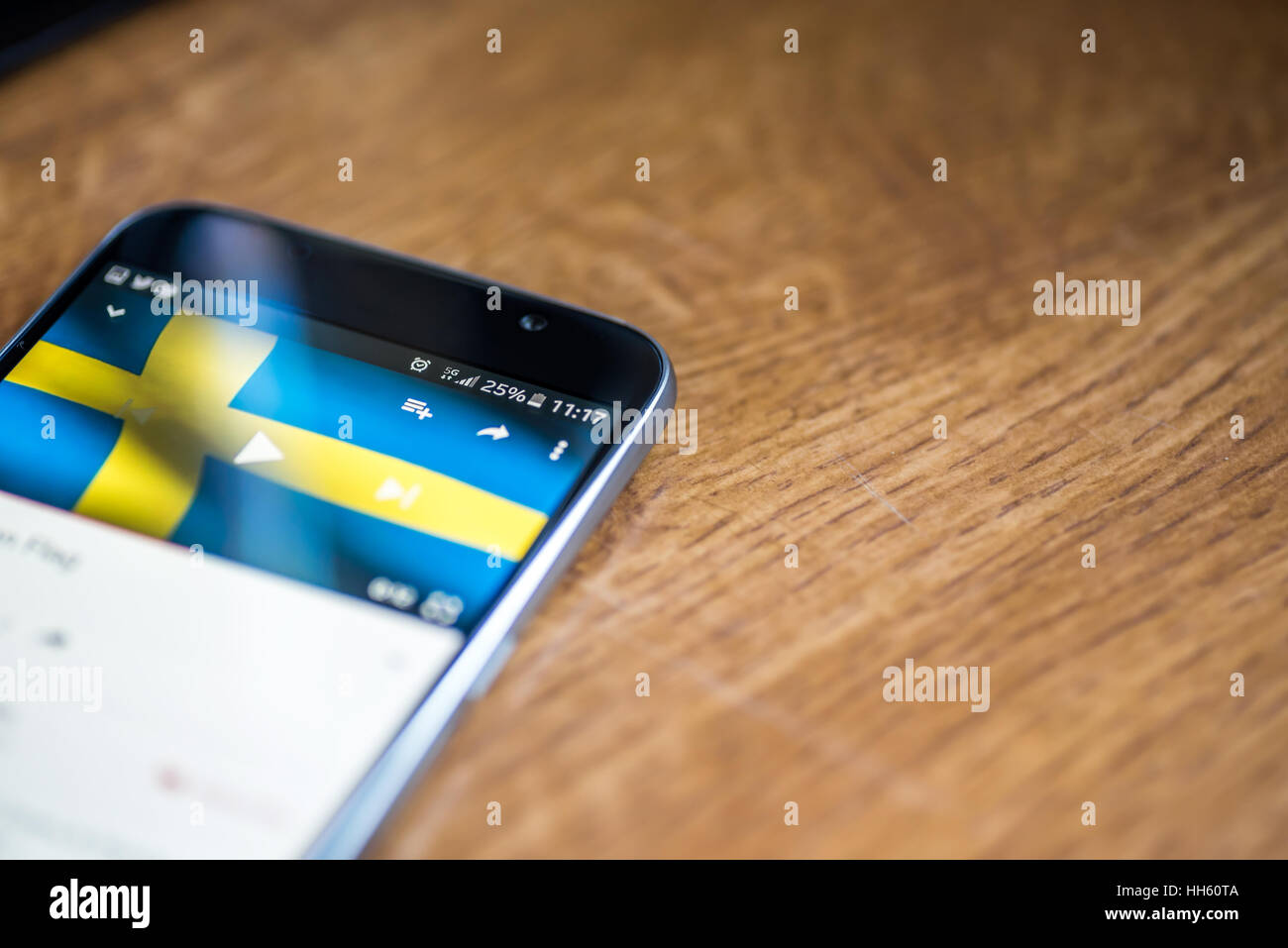 Sur fond de bois avec smartphone 5G Réseau inscription 25  % et la Suède drapeau sur l'écran. Banque D'Images