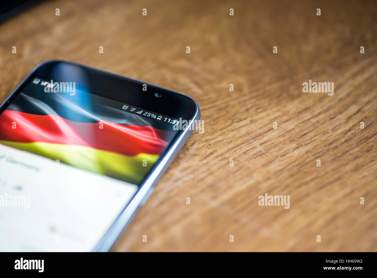 Sur fond de bois avec smartphone 5G Réseau inscription 25  % et drapeau allemand sur l'écran. Banque D'Images