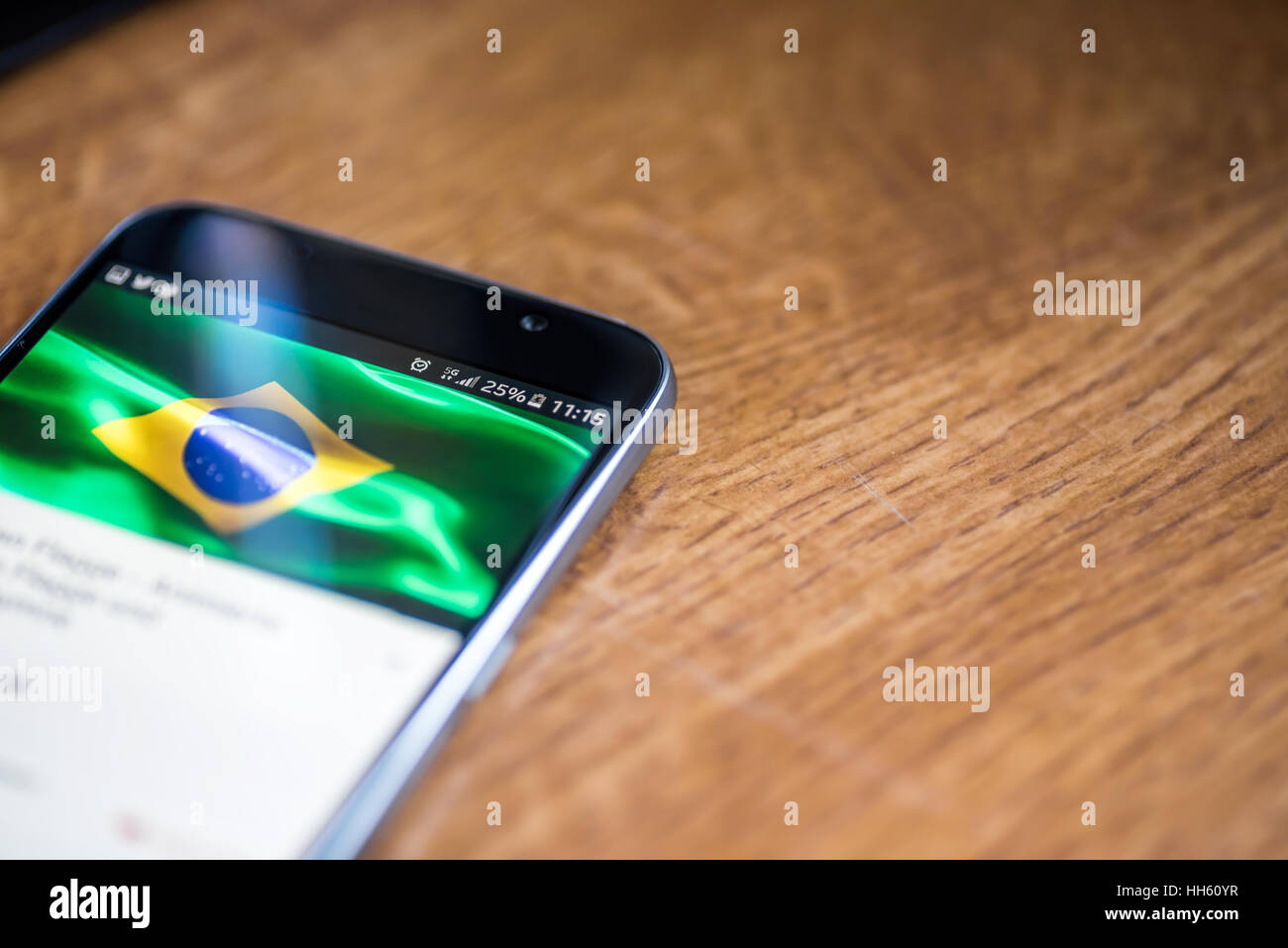 Sur fond de bois avec smartphone 5G Réseau inscription 25  % et le Brésil drapeau sur l'écran. Banque D'Images