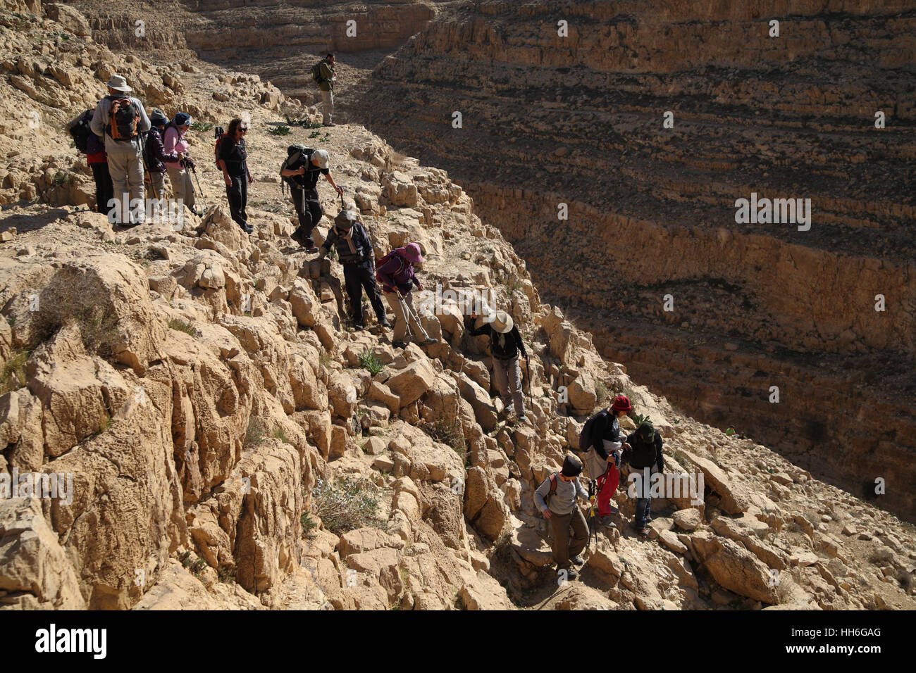Senior citizen les randonneurs sont soigneusement la descente d'une pente raide dans le canyon profond de Nahal ou Nahal Kina, le désert de Judée. Banque D'Images