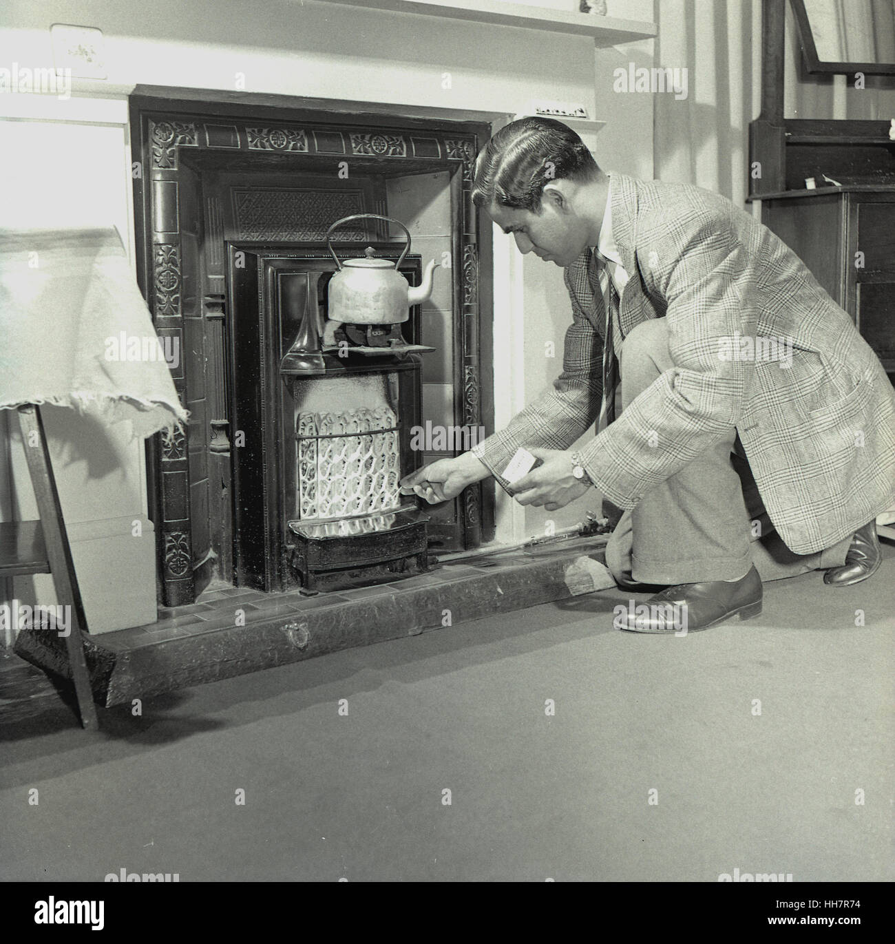1950, historiques, nouvellement arrivés à l'étranger étudiant indien à l'Institut de l'éducation (OIE) tente d'allumer un feu de gaz pour chauffer une bouilloire à son logis. Banque D'Images