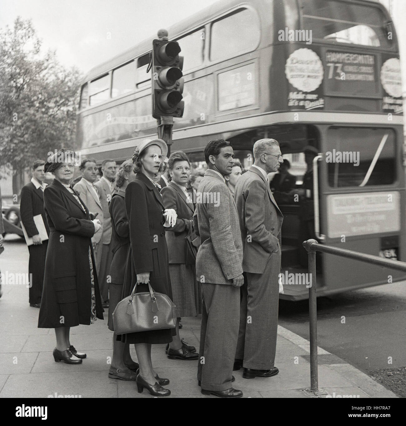 1950, historiques, nouvellement arrivés à l'étranger étudiant indien à l'Institut de l'éducation (OIE) attend avec d'autres britanniques pour un bus, Londres, Angleterre. Banque D'Images