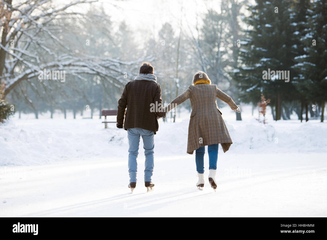 Senior couple in sunny winter nature glace Patinage, vue arrière. Banque D'Images