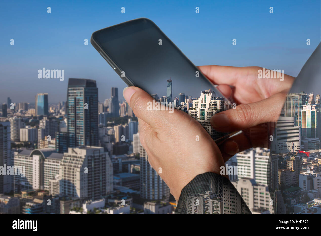 Double exposition femme de main courante et de l'écran tactile du téléphone intelligent, tablette,cellulaire et un jour paysage urbain Banque D'Images