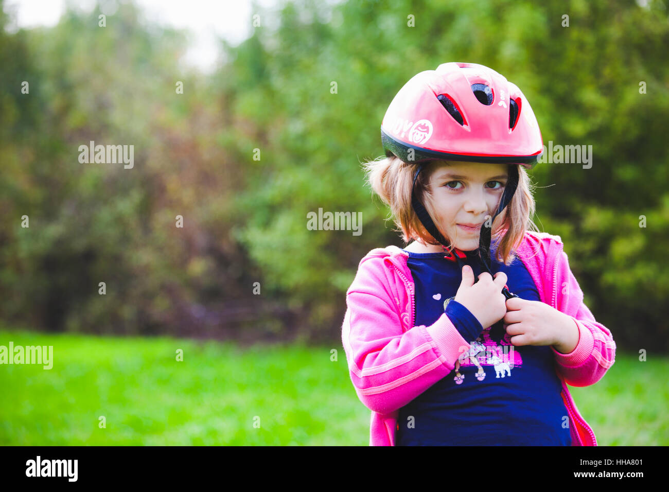 Jeune fille avec casque à vélo sur la tête dans le parc Banque D'Images