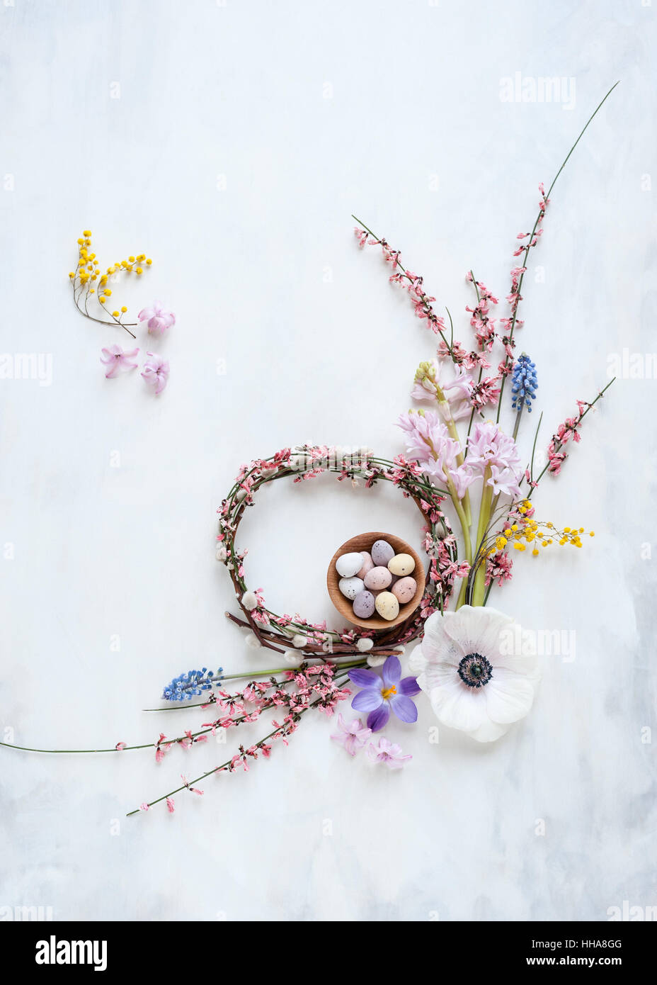 Couronne de printemps avec des fleurs et des mini oeufs dans un bol, lumière naturelle, vue de dessus, sur fond gris et blanc peint Banque D'Images