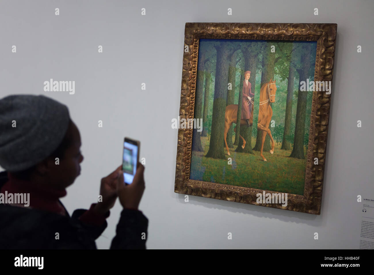 Visiteur utilise son smartphone pour photographier le tableau Le Blanc-Seing  (la signature en blanc, 1965) par l'artiste surréaliste belge René Magritte  affichée à son exposition rétrospective au Centre Pompidou à Paris, France.
