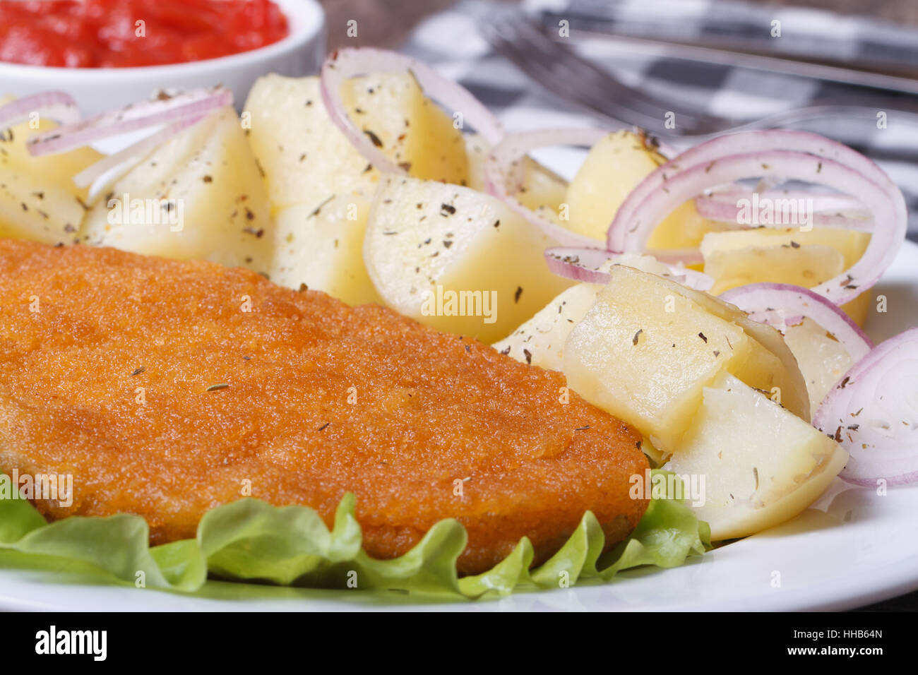 Schnitzel avec de jeunes pommes de terre bouillies et d'oignons sur une assiette blanche horizontale. Gros plan macro. Banque D'Images