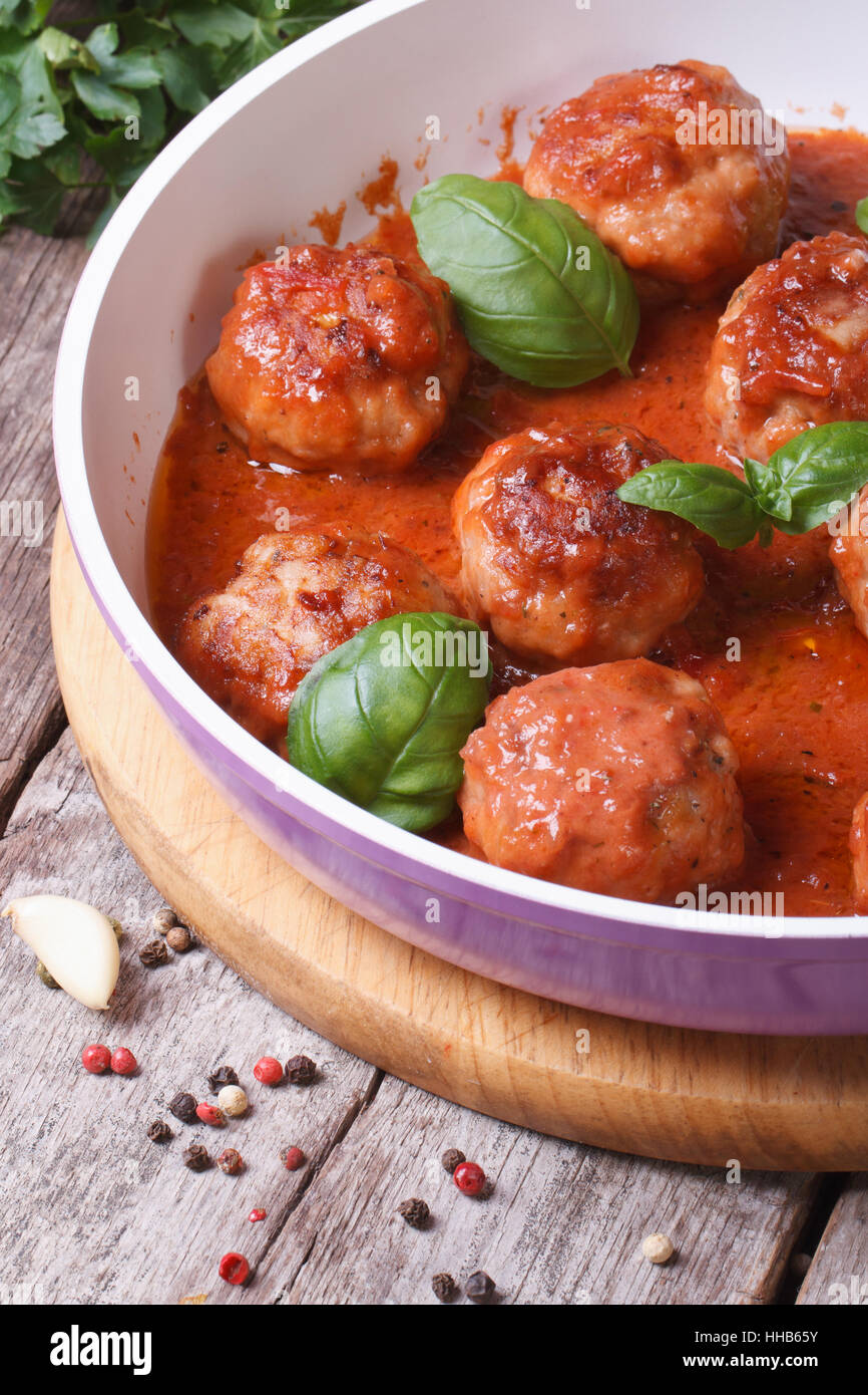 Petites boulettes de viande avec sauce tomate et basilic dans une casserole sur une table de bois à la verticale Banque D'Images