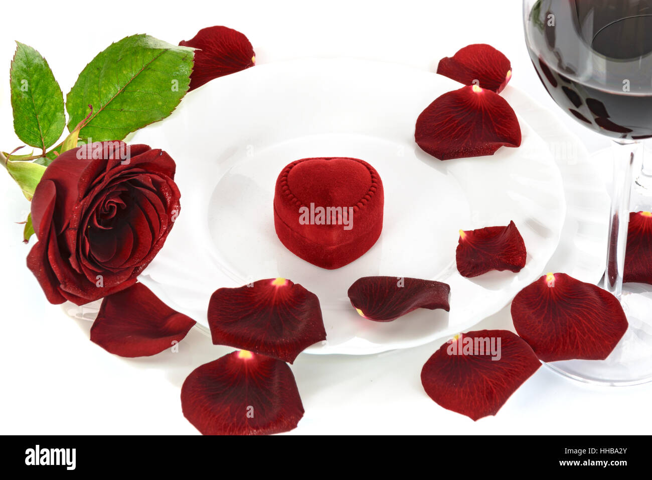 Réglage de la table pour un dîner romantique de la Saint-Valentin avec une rose rouge, le vin rouge et le don. Banque D'Images