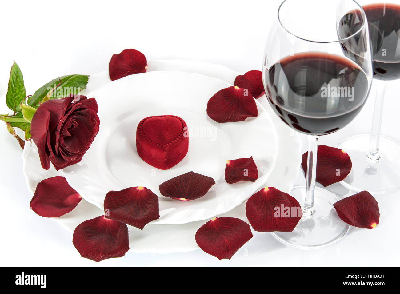 Réglage de la table pour un dîner romantique de la Saint-Valentin avec une rose rouge, le vin rouge et le don. Banque D'Images