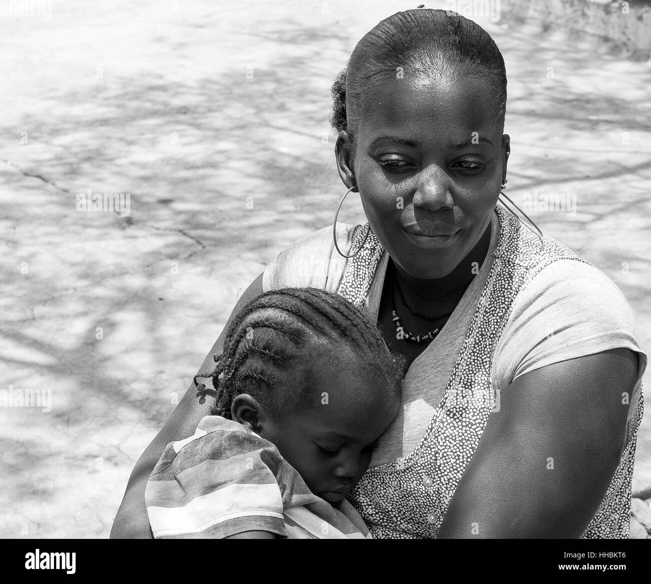 Maman noir tenant son bébé assis dans un square à Praia, Cap Vert. Banque D'Images