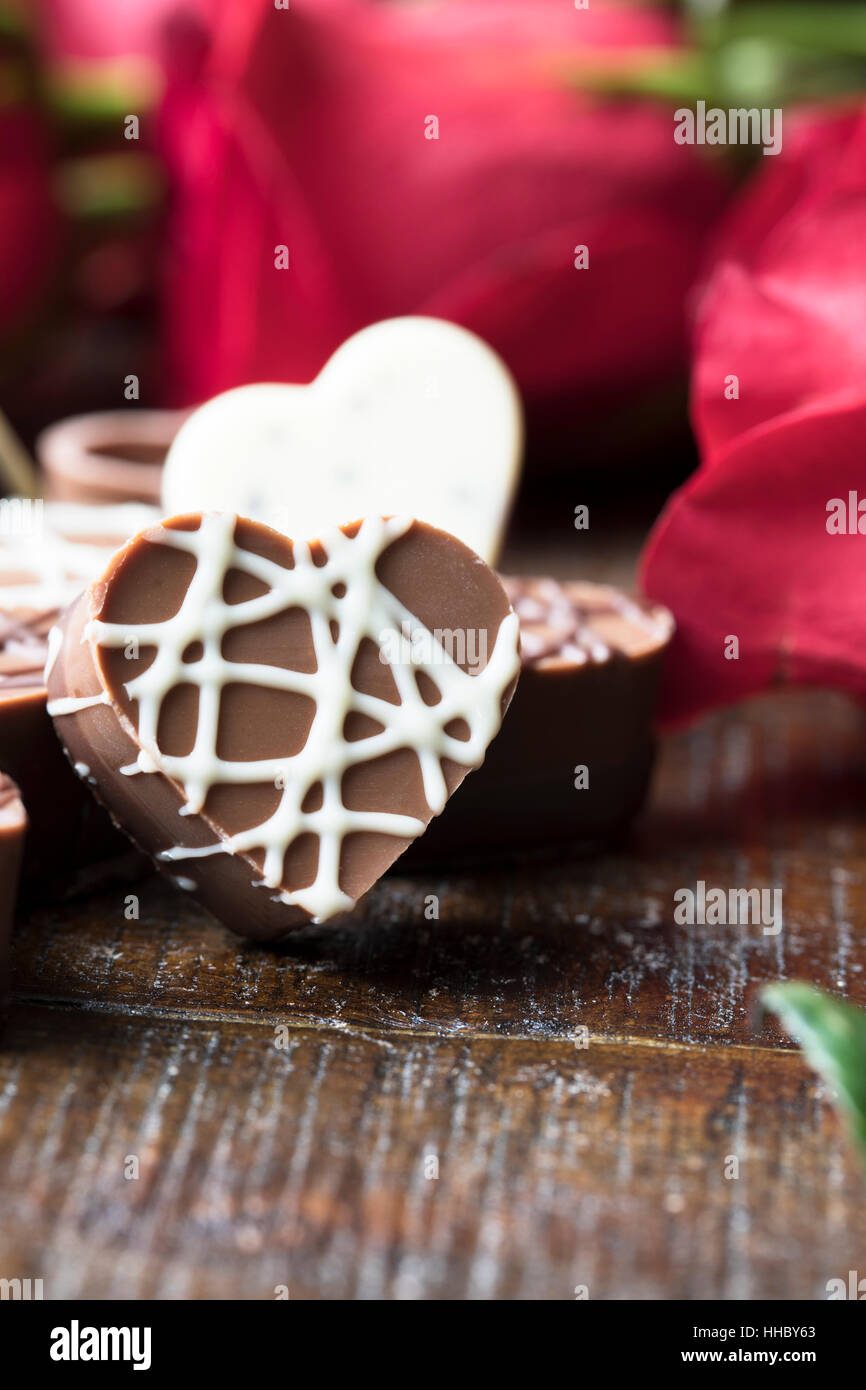 Close up de chocolat en forme de coeur avec des roses rouges à l'arrière-plan. Banque D'Images