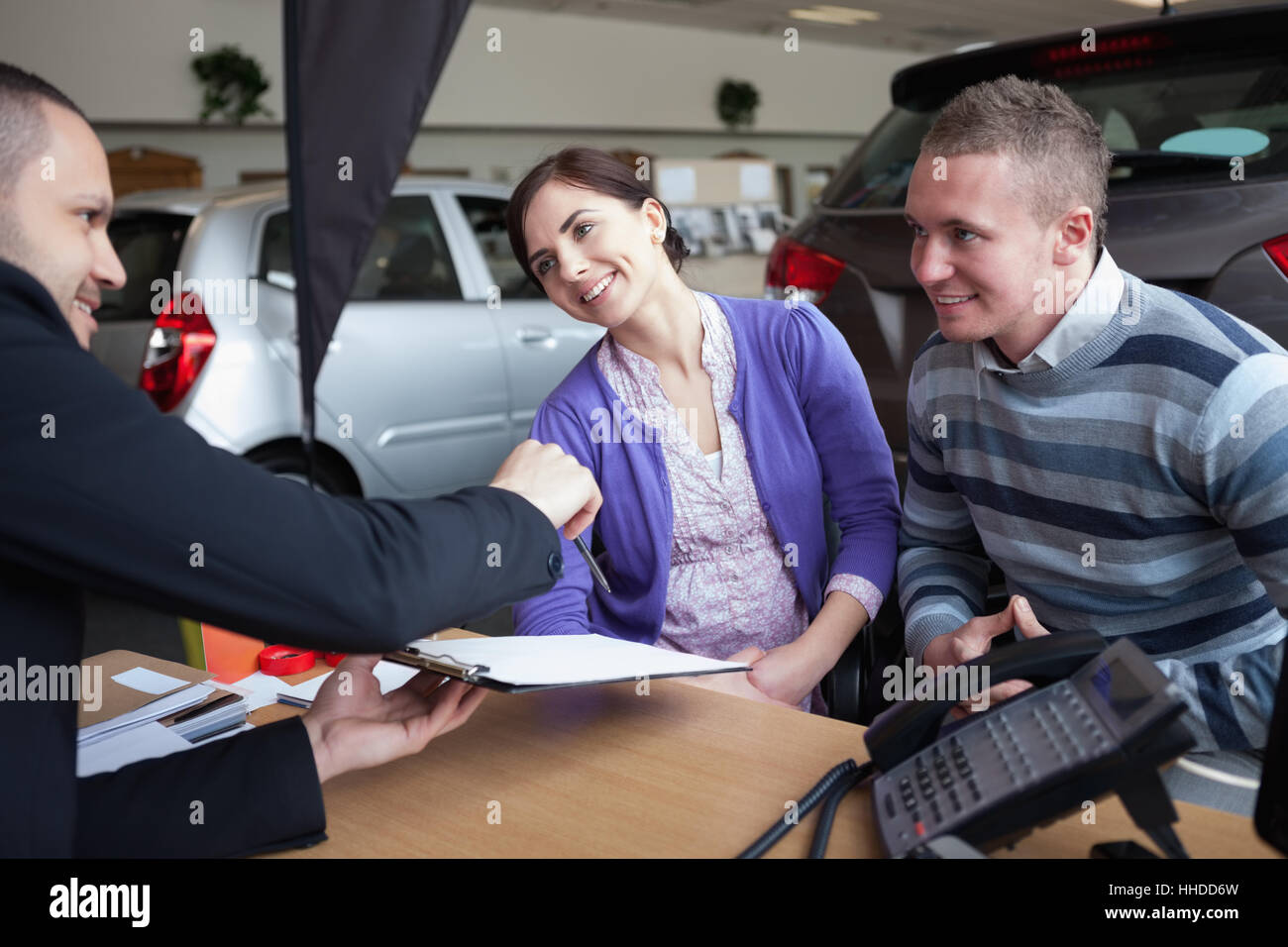 Couple de discuter avec un vendeur de voiture dans un magasin de voitures Banque D'Images