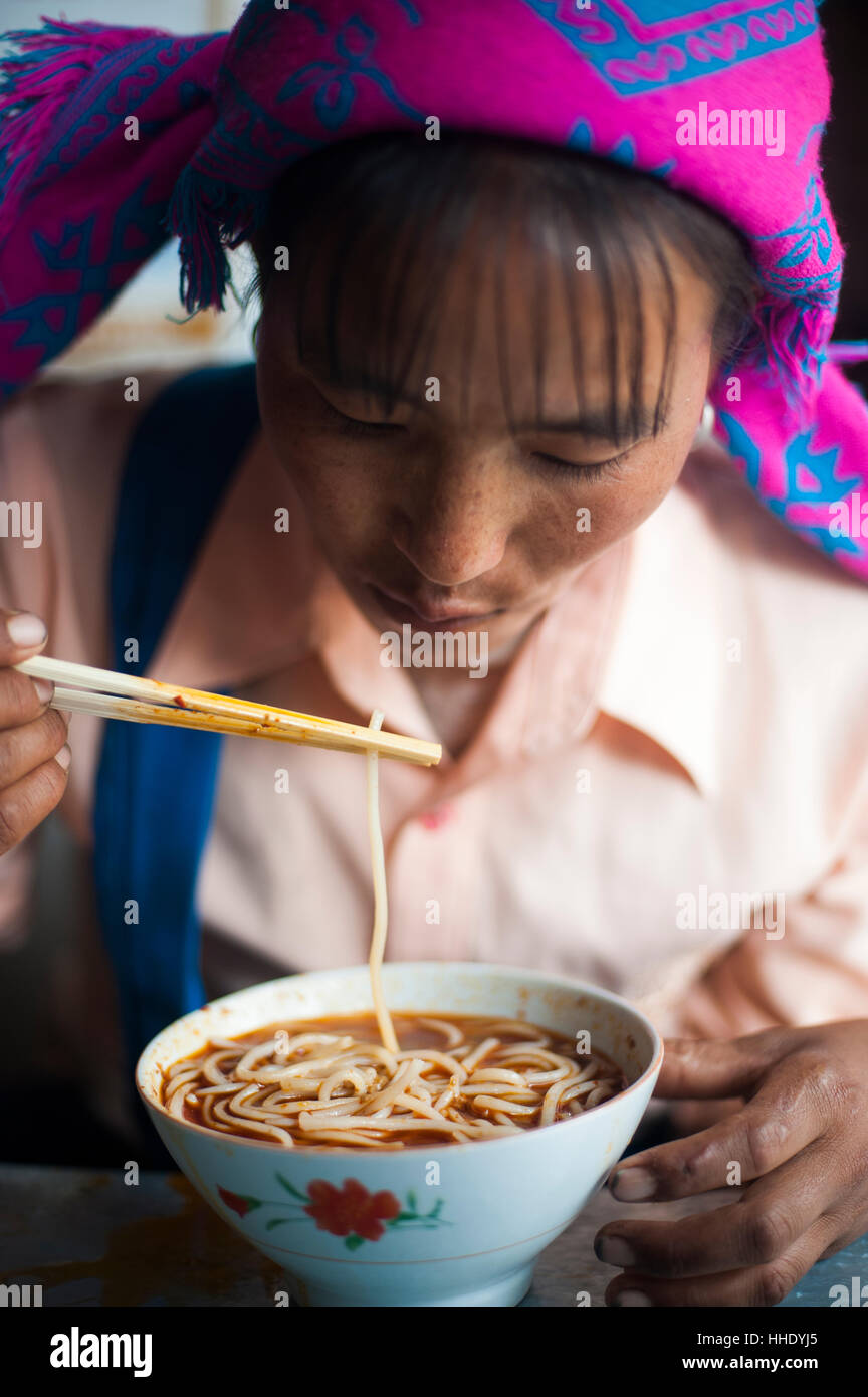 Une femme Miao mange un bol de nouilles dans la province de Yunnan, Chine Banque D'Images