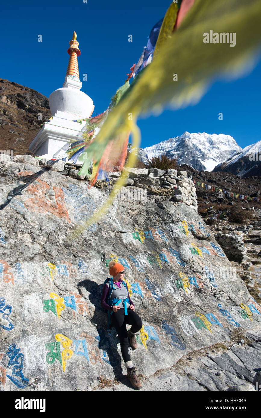 Une femme dans la vallée de Langtang trekking s'arrête près de Mani mur de pierre au-dessous d'un stupa bouddhiste avec les drapeaux de prières, Népal Banque D'Images