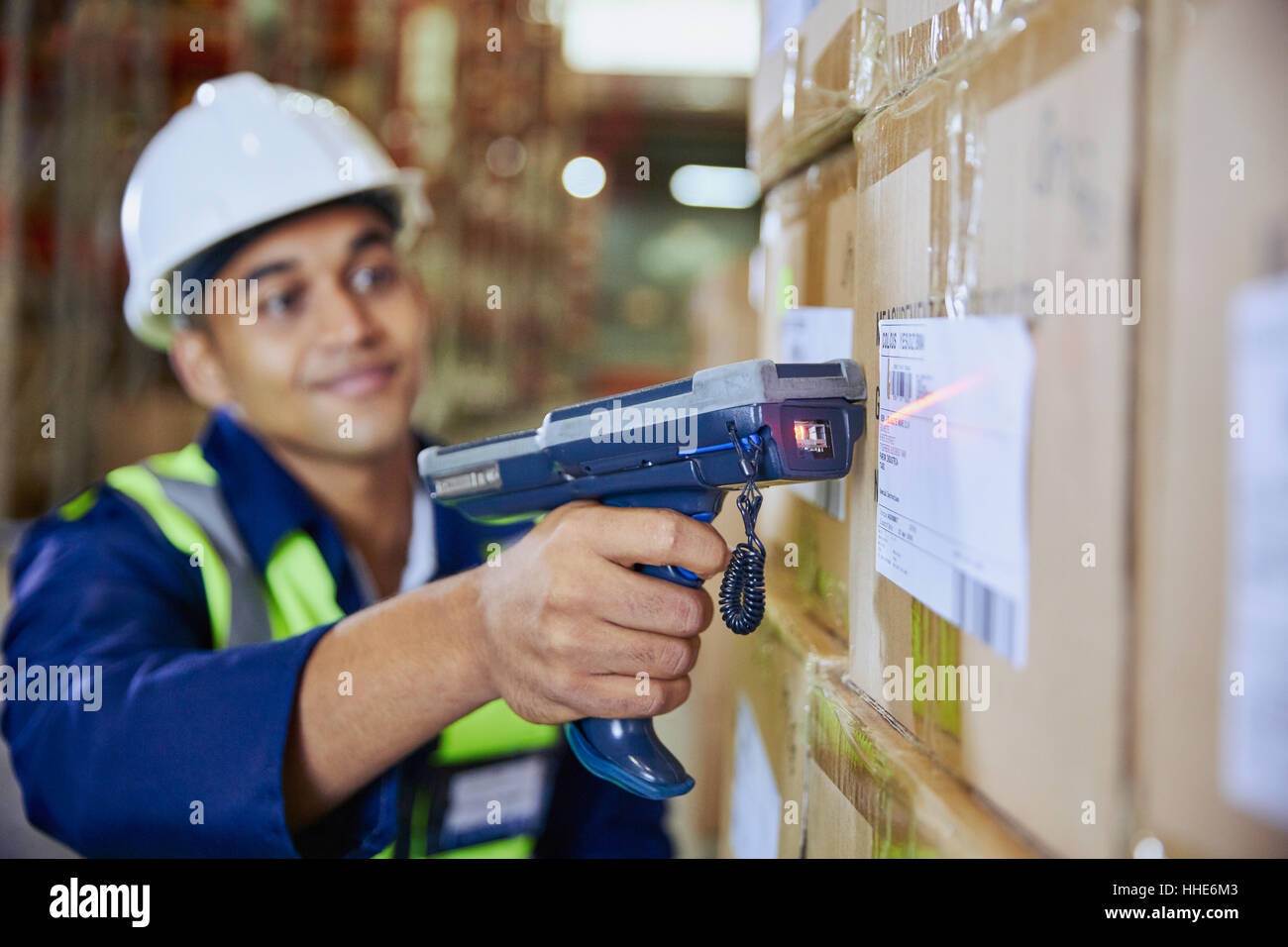 Travailleur avec code à barres de numérisation du scanner sur fort dans l'entrepôt de distribution Banque D'Images