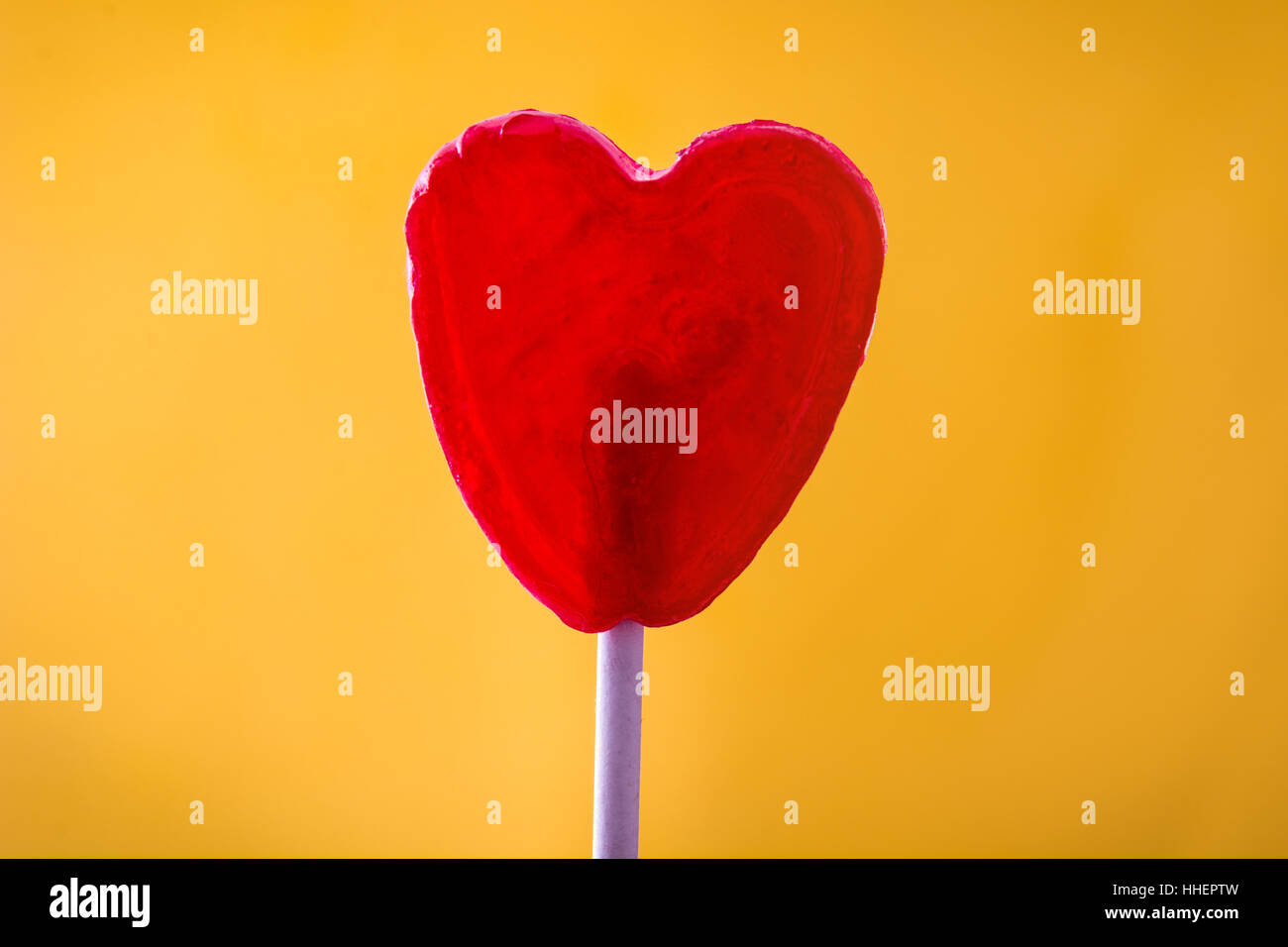 Sucette rouge en forme de coeur avec sur fond jaune. Concept d'amour. Le jour de la Saint-Valentin. Banque D'Images