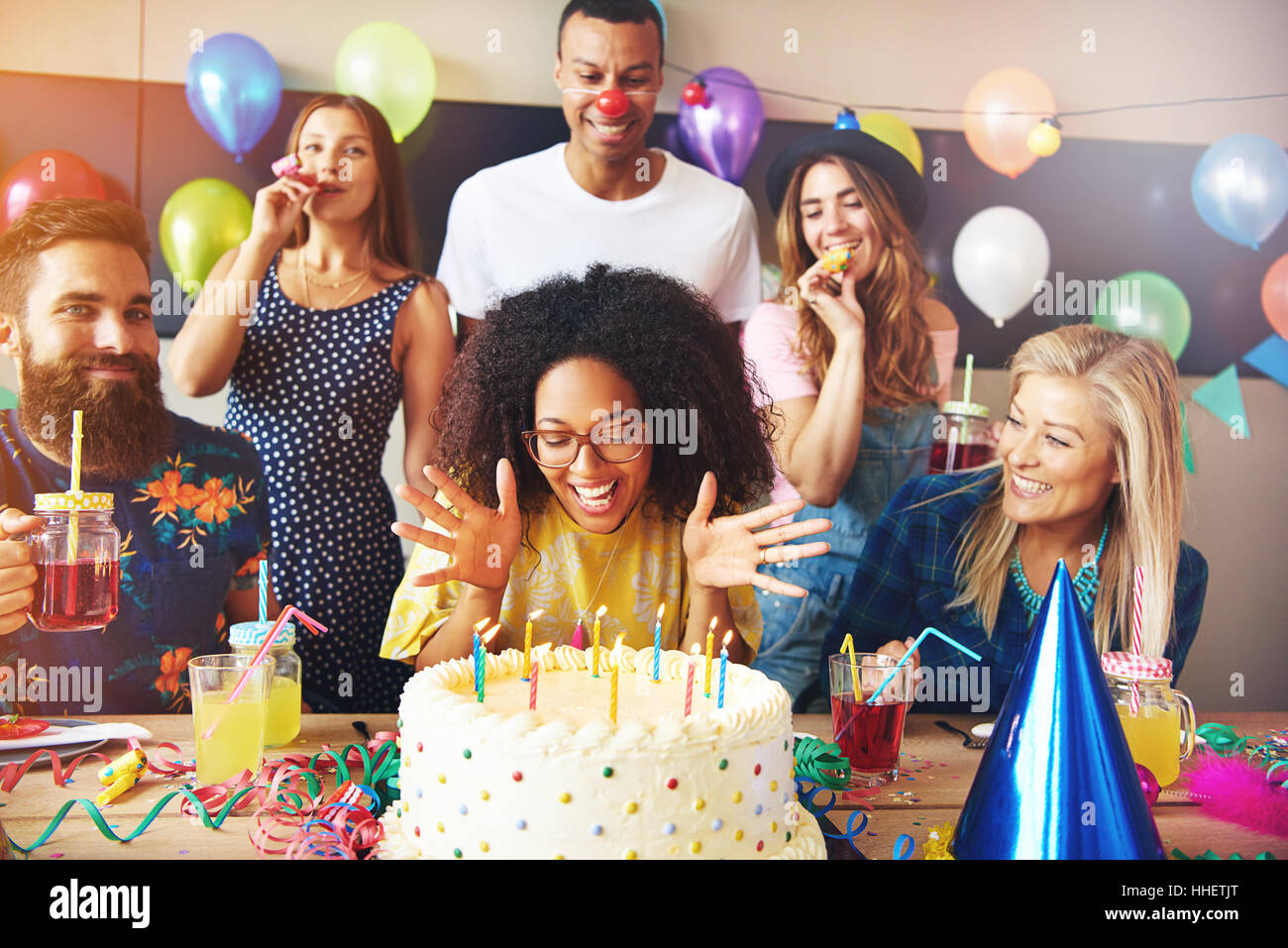 Jeune Femme Africaine Vivace Celebrant Son Anniversaire S Apprete A Souffler Les Bougies Sur Le Gateau Vu Par Un Groupe D Amis Photo Stock Alamy