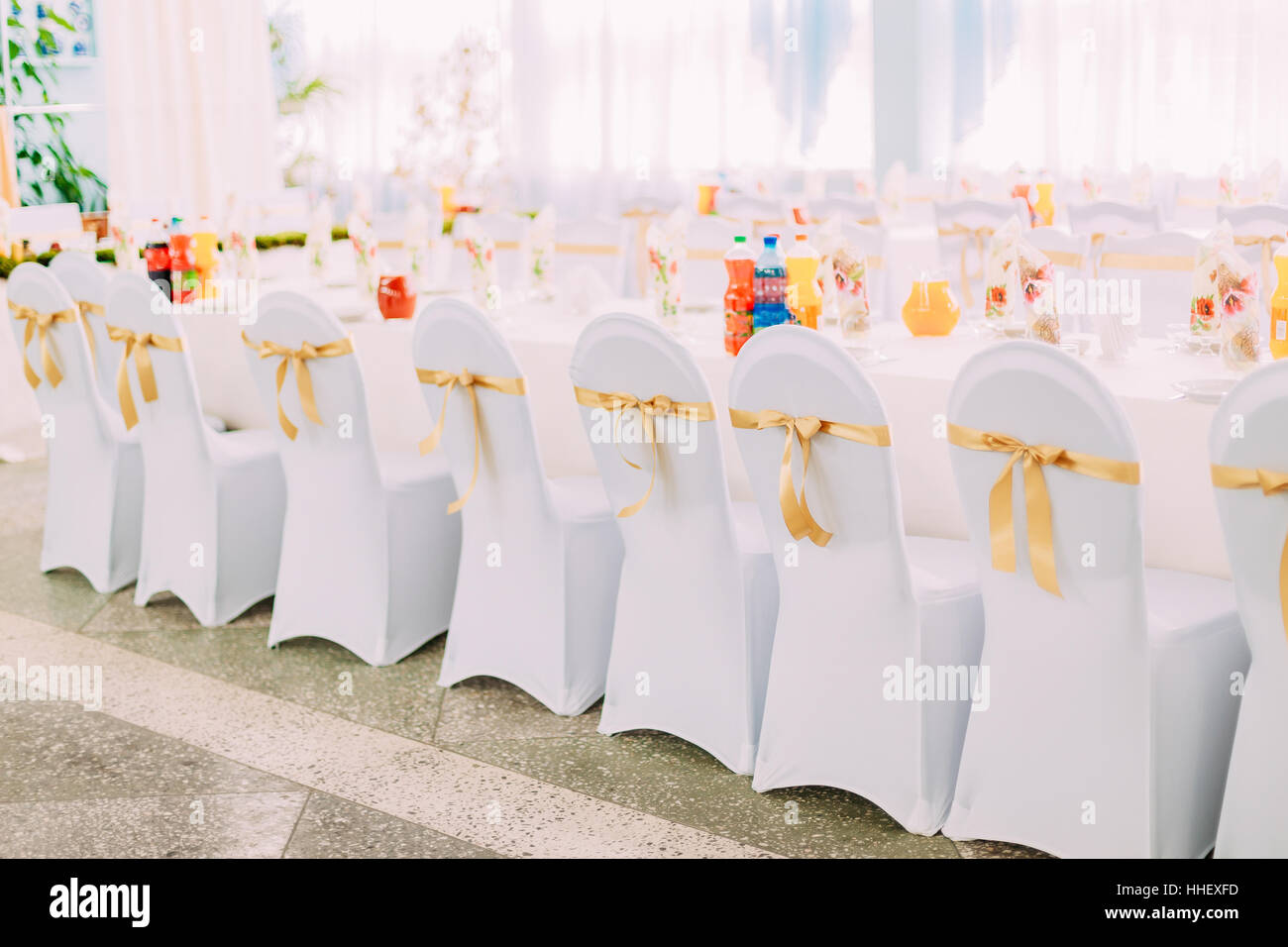 Manteaux blanc décoratif et rubans de couleur sur des chaises à la table de fête. Des chaises et une table recouverte de tissu. Banque D'Images