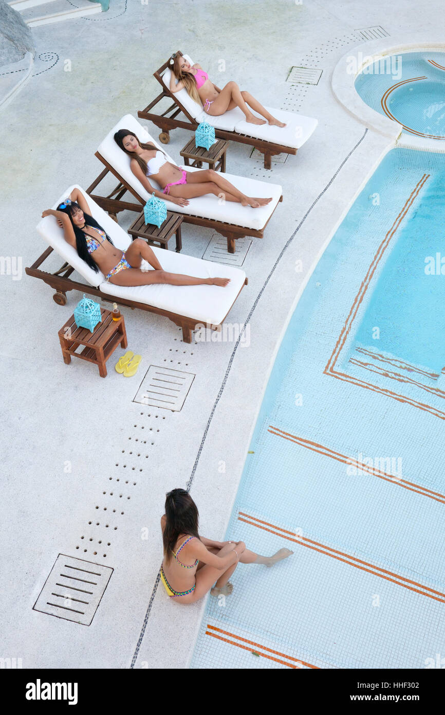 Quatre jeunes femmes bronzage et bénéficiant d'une piscine à jour Banque D'Images