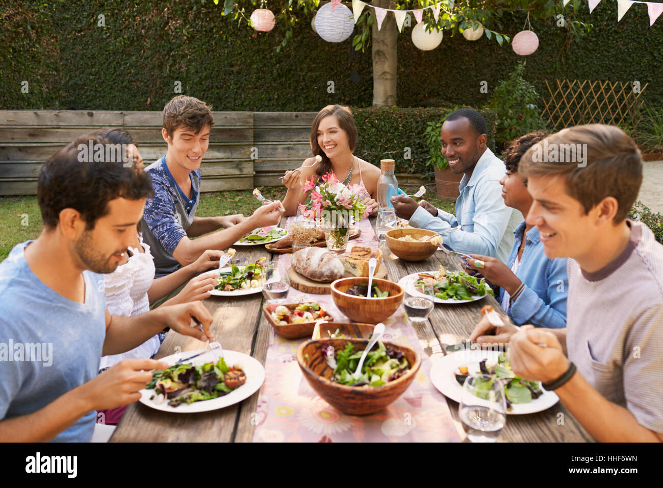 Les amis boire et manger autour de la table At Outdoor Party Banque D'Images