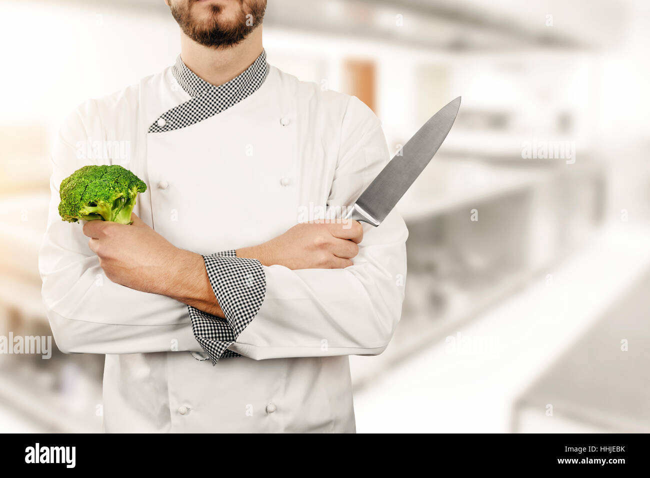 Chef dans une cuisine de restaurant avec brocoli et couteau en mains Banque D'Images