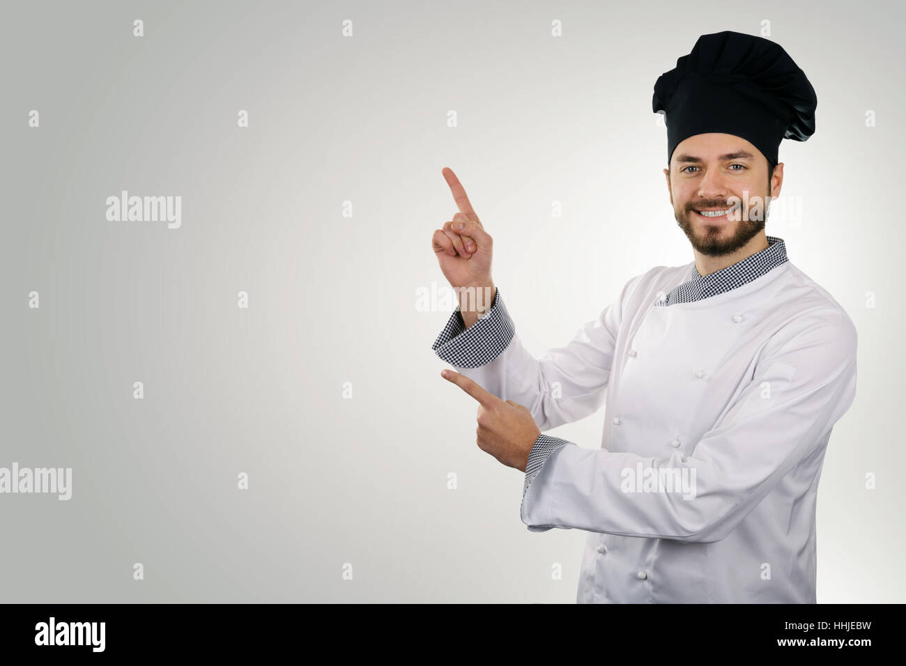Young happy chef pointant sur copy space Banque D'Images