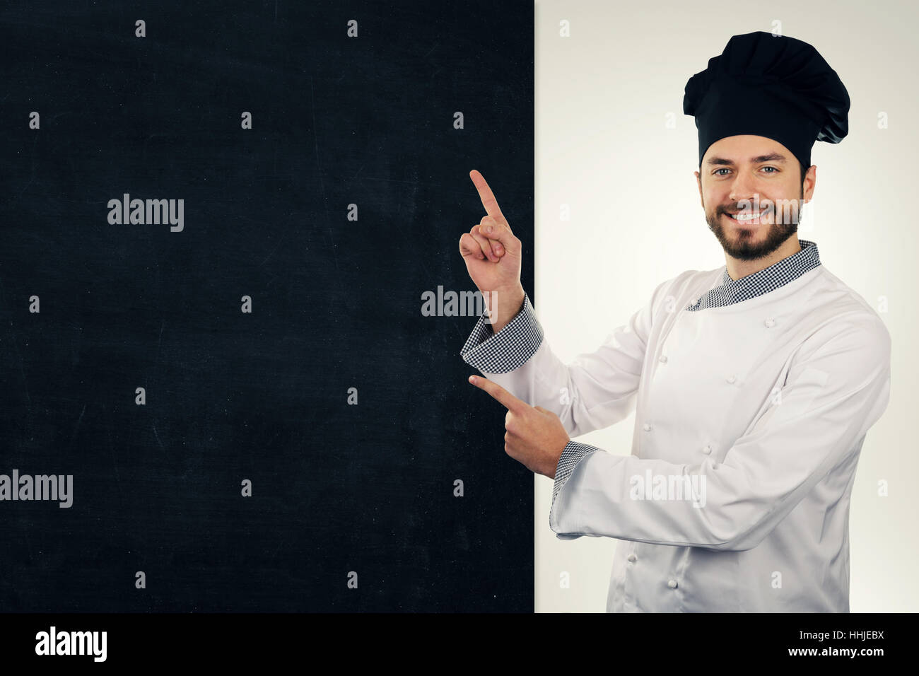 Young smiling cook pointant sur le tableau blanc. copy space Banque D'Images