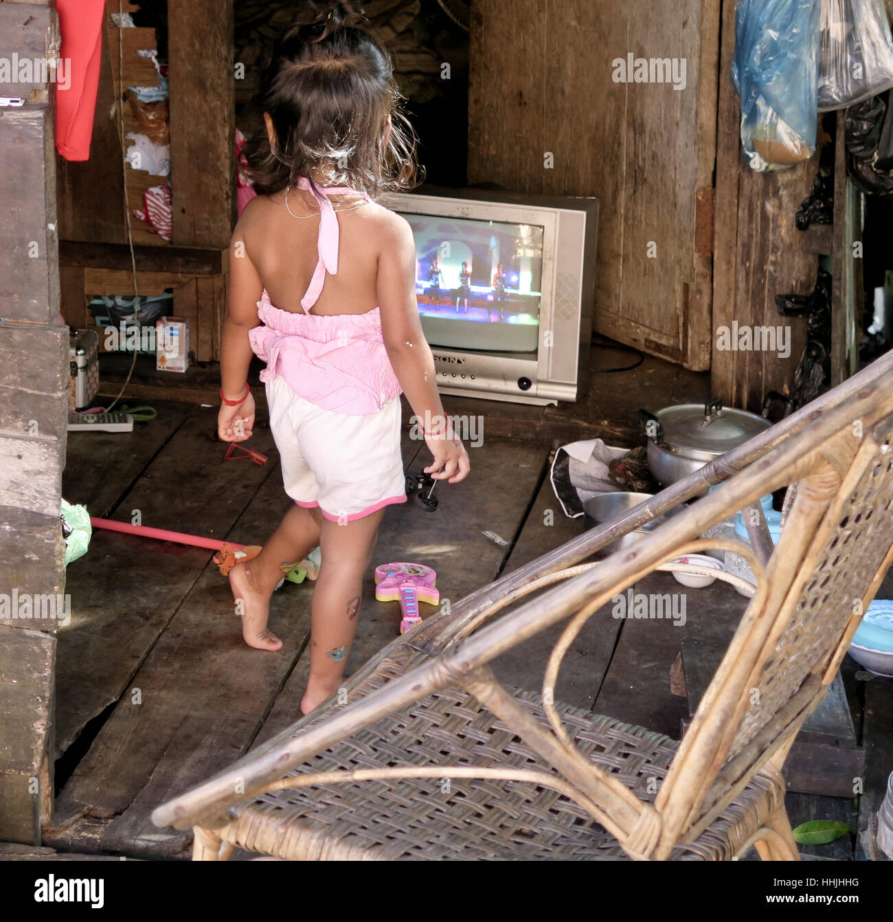 Petite fille cambodgienne danser tout en regardant la télévision dans sa maison au Cambodge. Malgré qu'elle est si pauvre, elle peut encore profiter de la danse. Banque D'Images