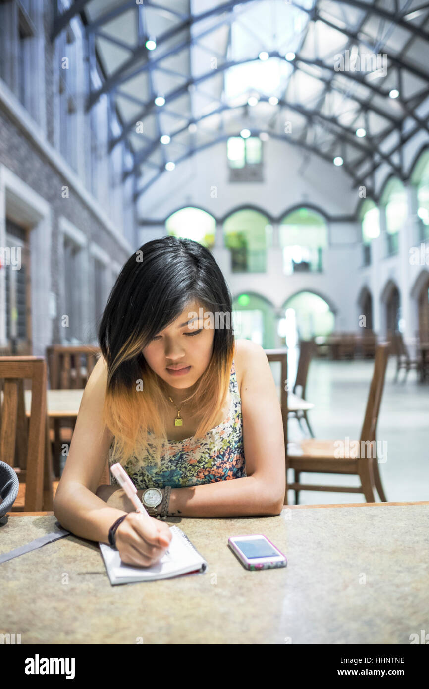 Chinese woman sitting in library écrit dans l'ordinateur portable Banque D'Images