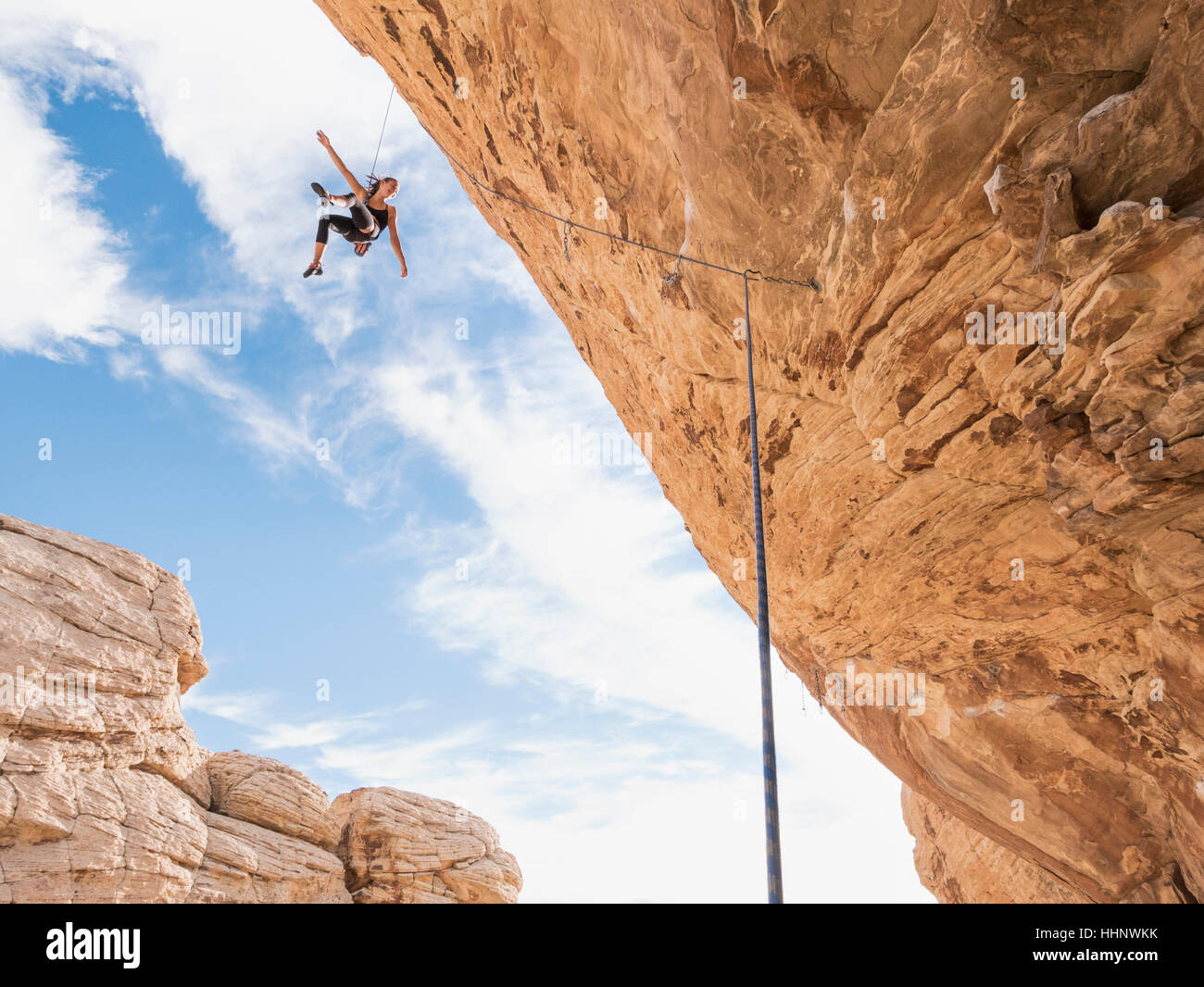 Mixed Race girl hanging from rope tandis que l'escalade de rocher Banque D'Images