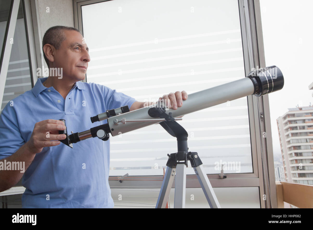 Hispanic man holding fenêtre près de télescope Banque D'Images