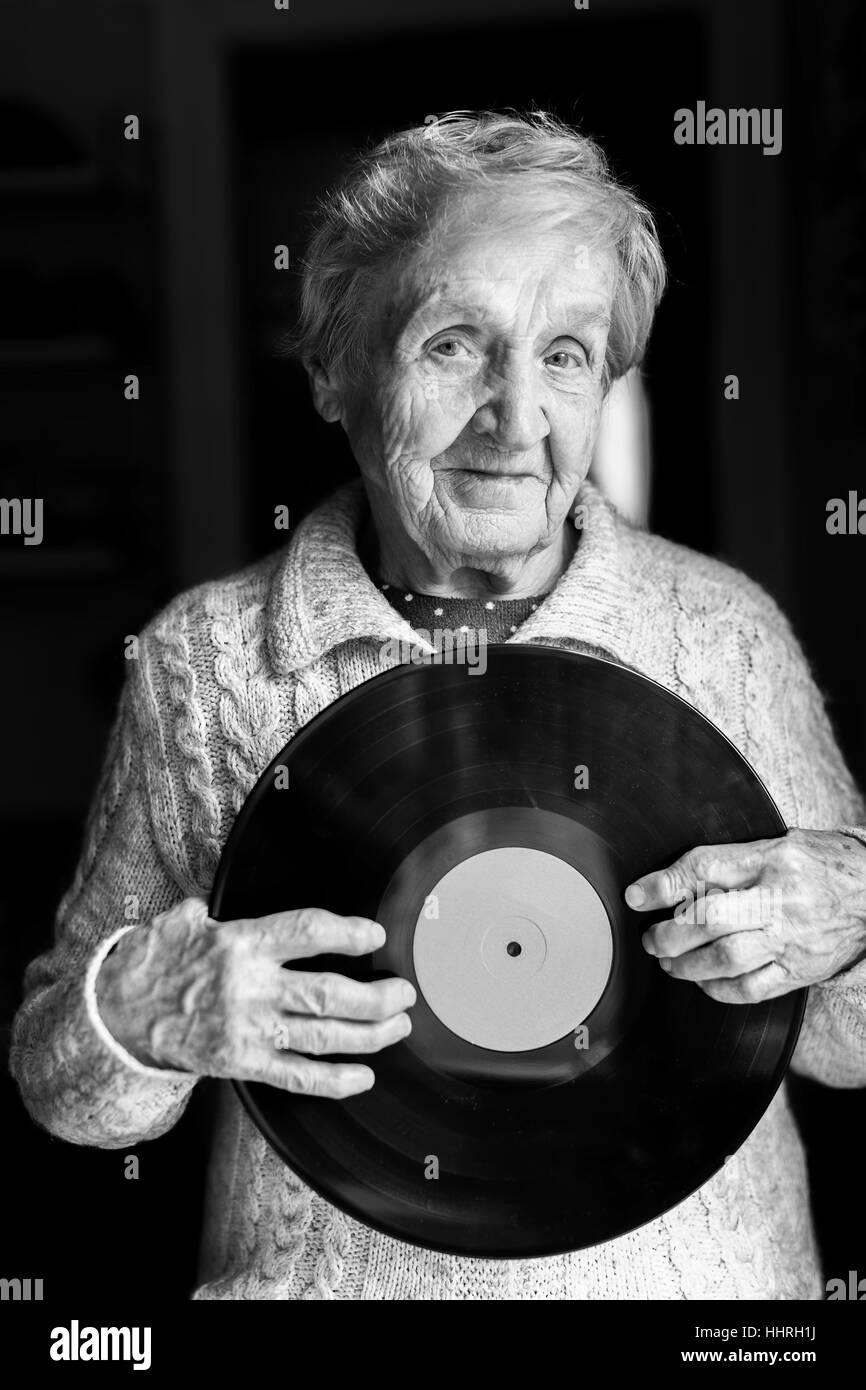 Femme âgée avec disque vinyle LP dans ses mains. Le noir et blanc. Banque D'Images