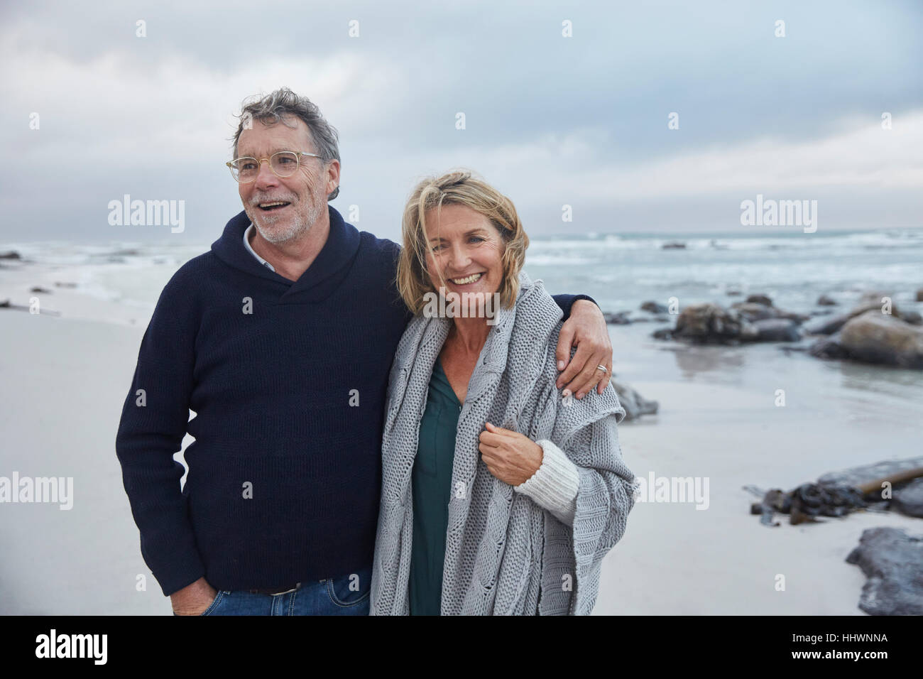Portrait of smiling senior couple hugging on beach orageux Banque D'Images