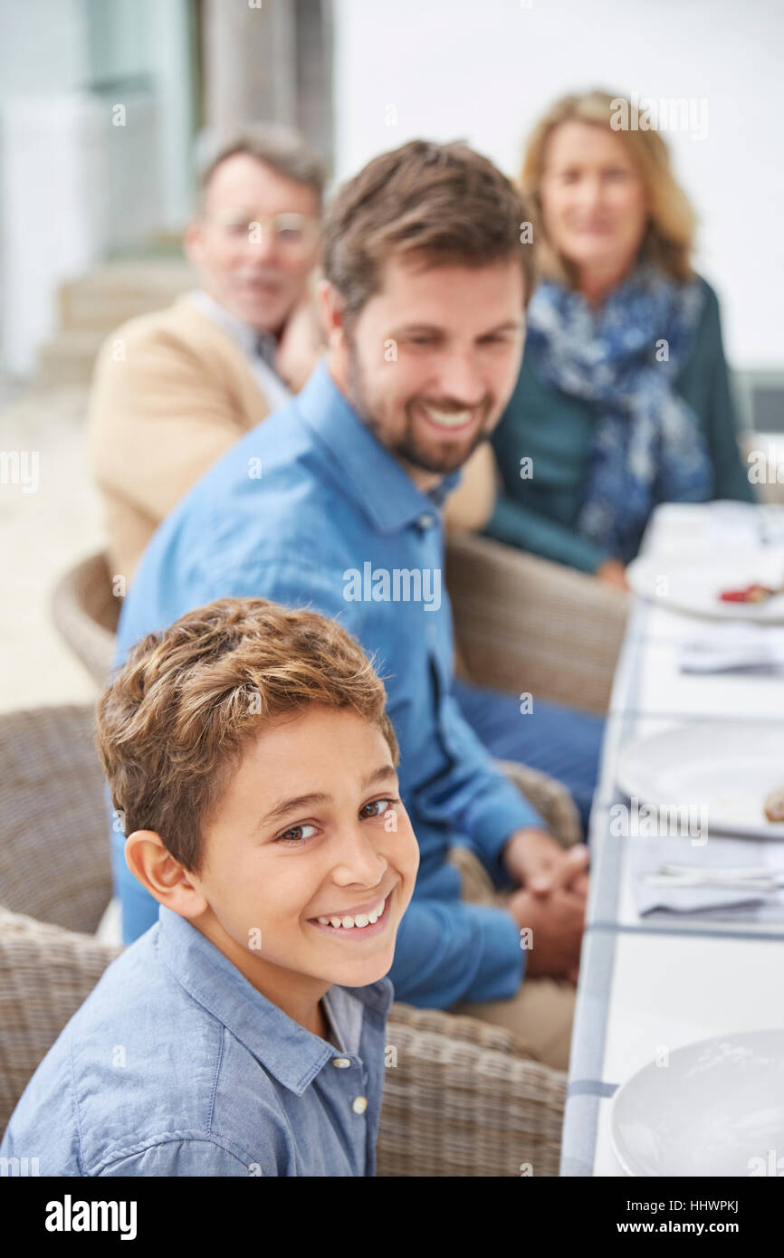Portrait smiling boy appréciant le déjeuner avec la famille on patio Banque D'Images