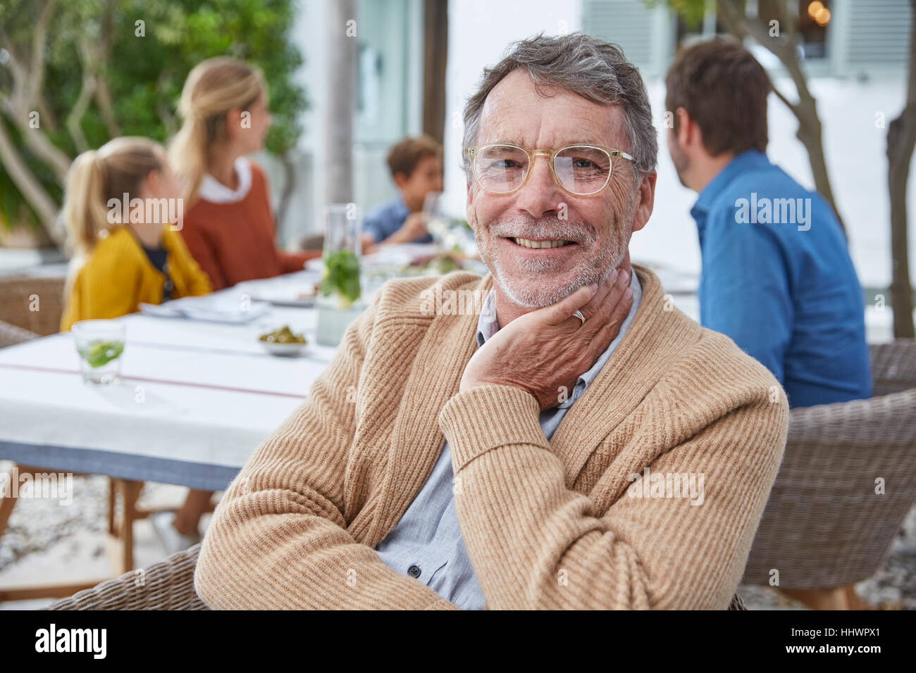 Portrait of smiling senior man enjoying patio le déjeuner avec la famille Banque D'Images