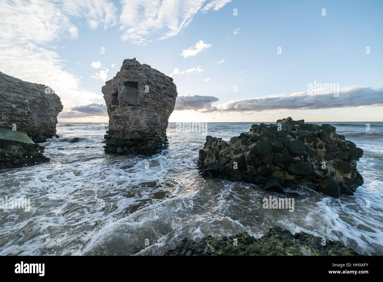 Le concassage des pierres et des vagues ruines du vieux fort au coucher du soleil sur la plage Banque D'Images