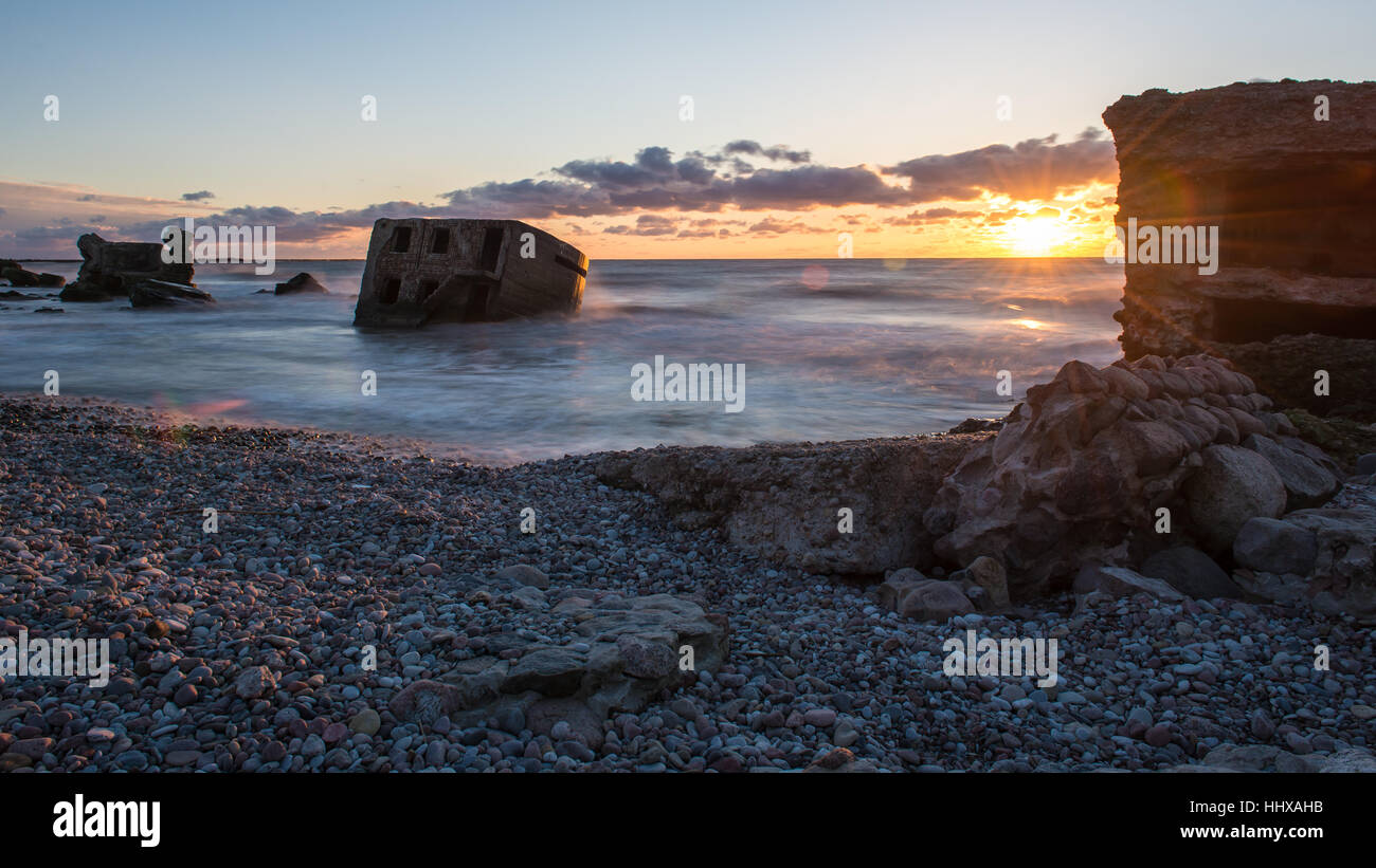 Le concassage des pierres et des vagues ruines du vieux fort au coucher du soleil sur la plage Banque D'Images